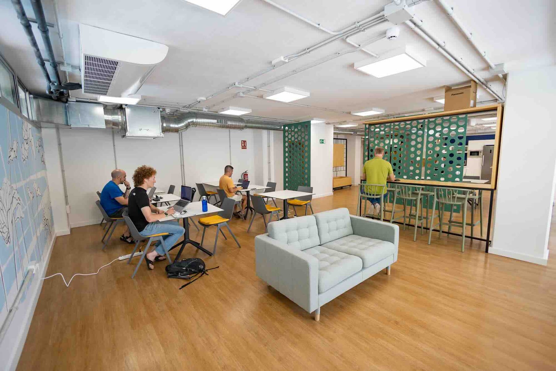 Zona de coworking con varios grupos de puestos y gente trabajando.