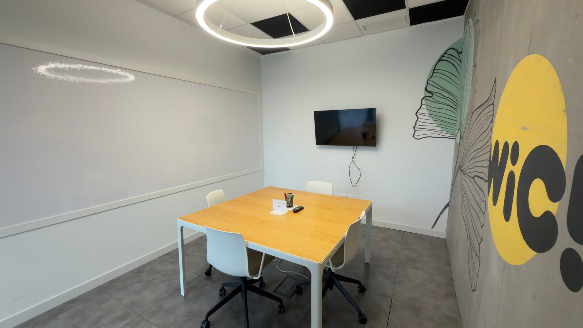 Sala de reuniones flop de WiC! La Minilla, con mesa para cuatro, pantalla y pizarra.
